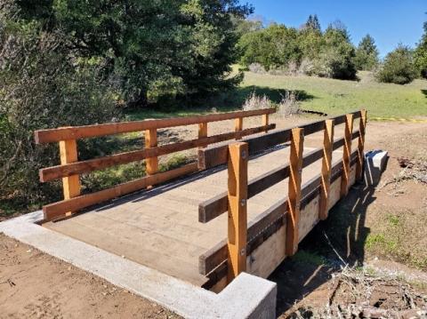 Wooden bridge connected to dirt trail