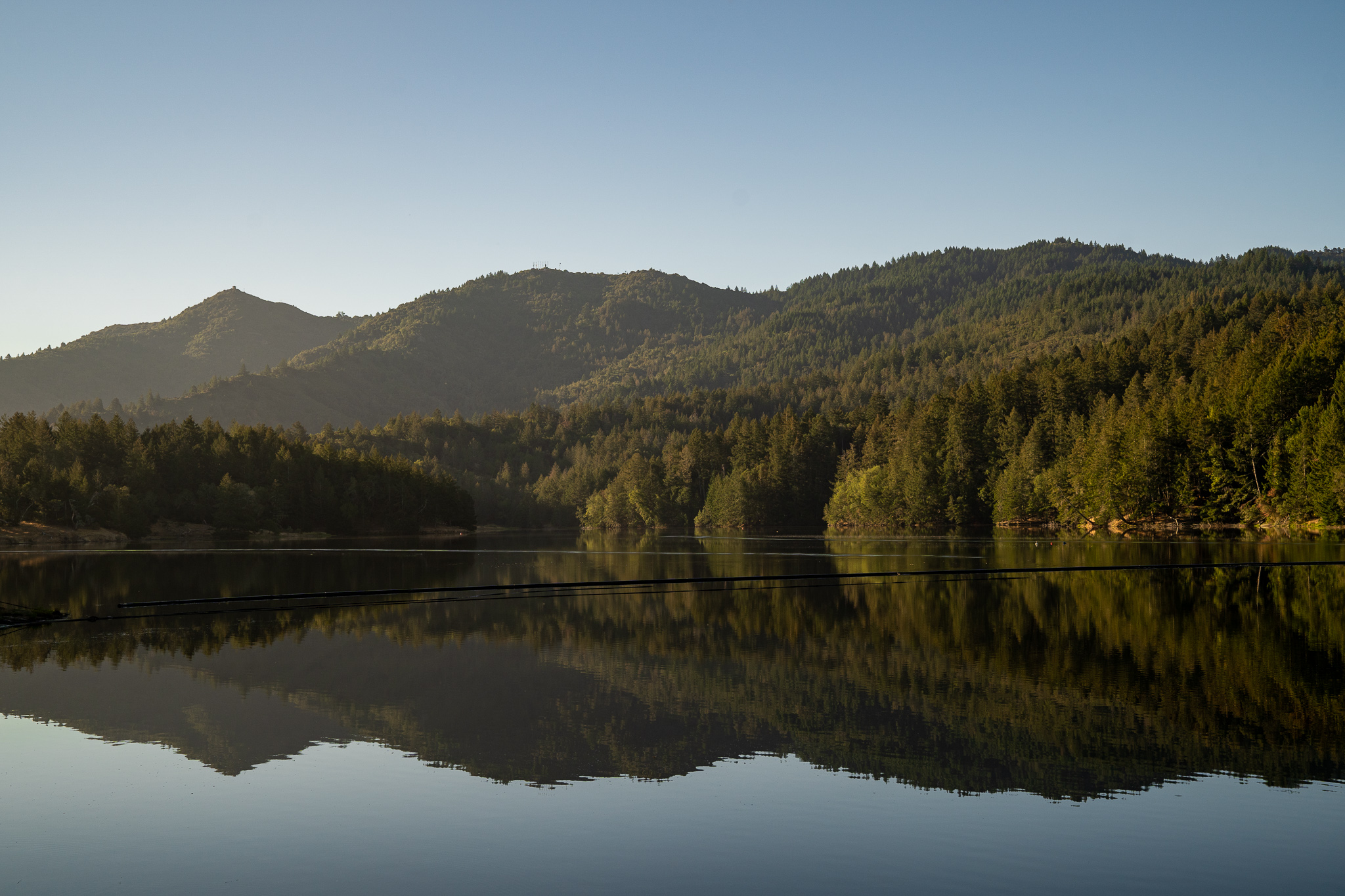 A lake reflects the tree-lined hillsides of the Mount Tamalpais Watershed. 