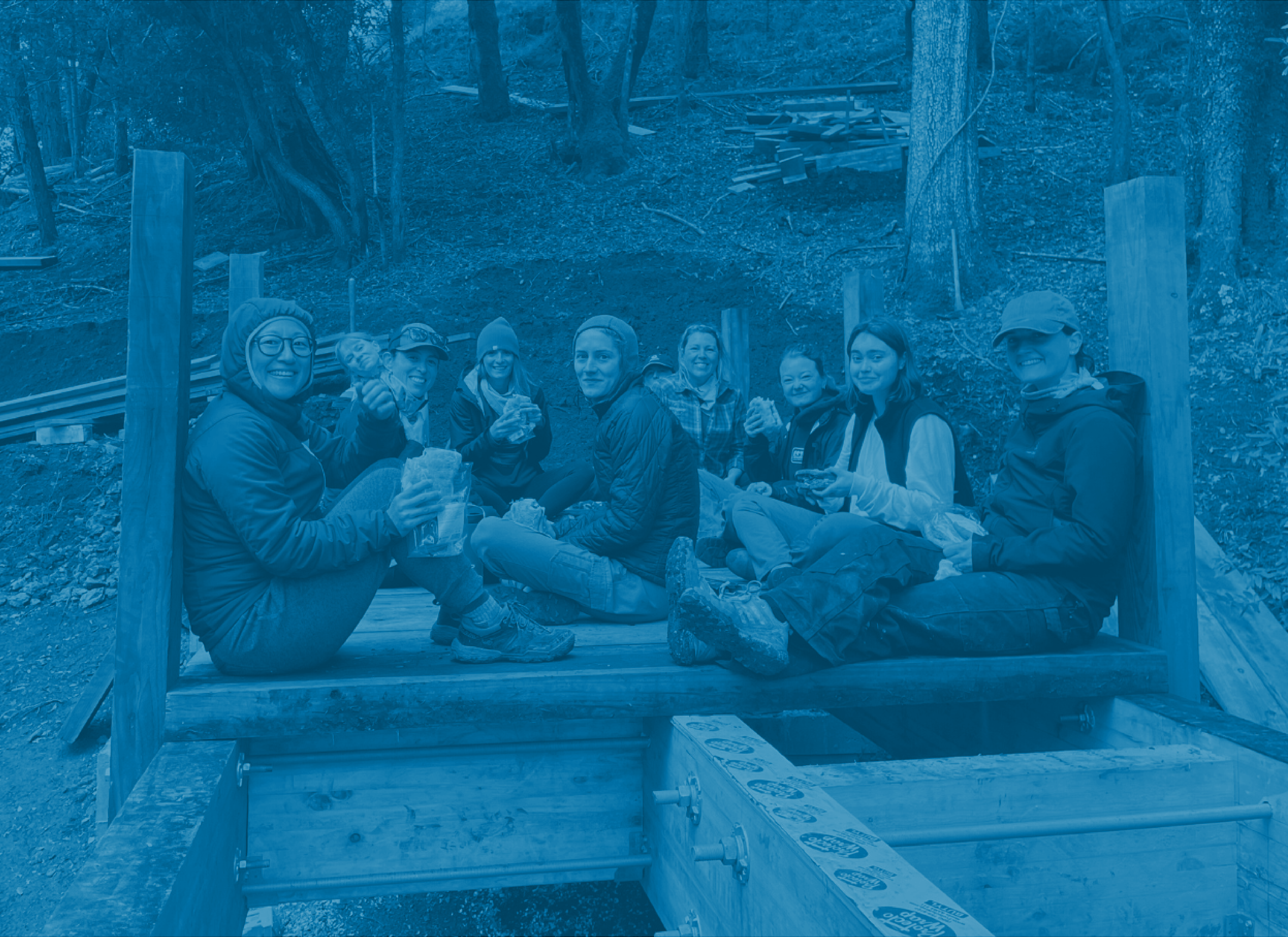 Registration button image showing volunteers eating lunch on a bridge