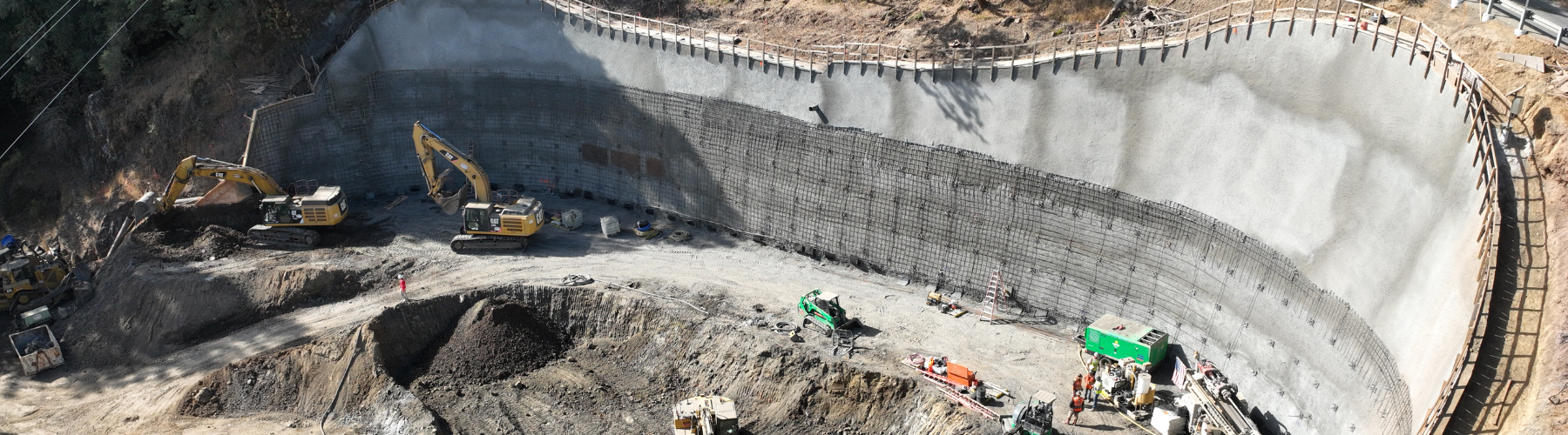 Image shows construction activity at a large, concrete wall.