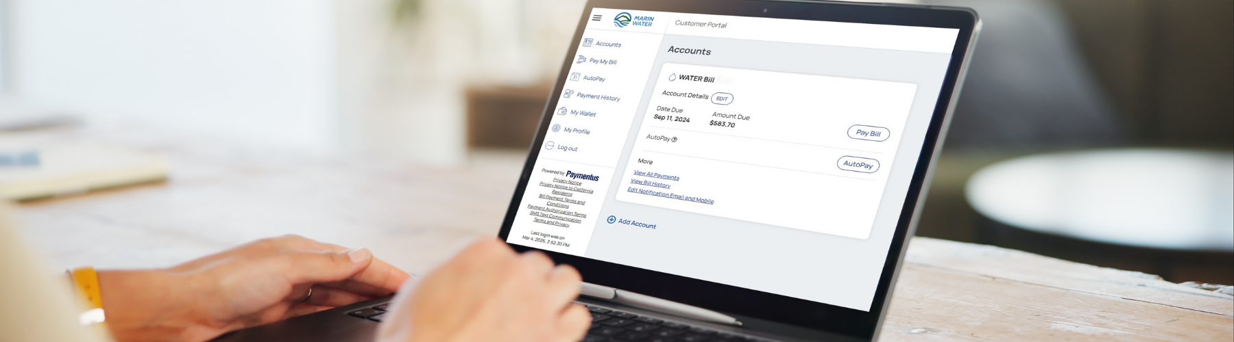 Hands on a laptop keyboard with the laptop screen displaying an online bill pay portal