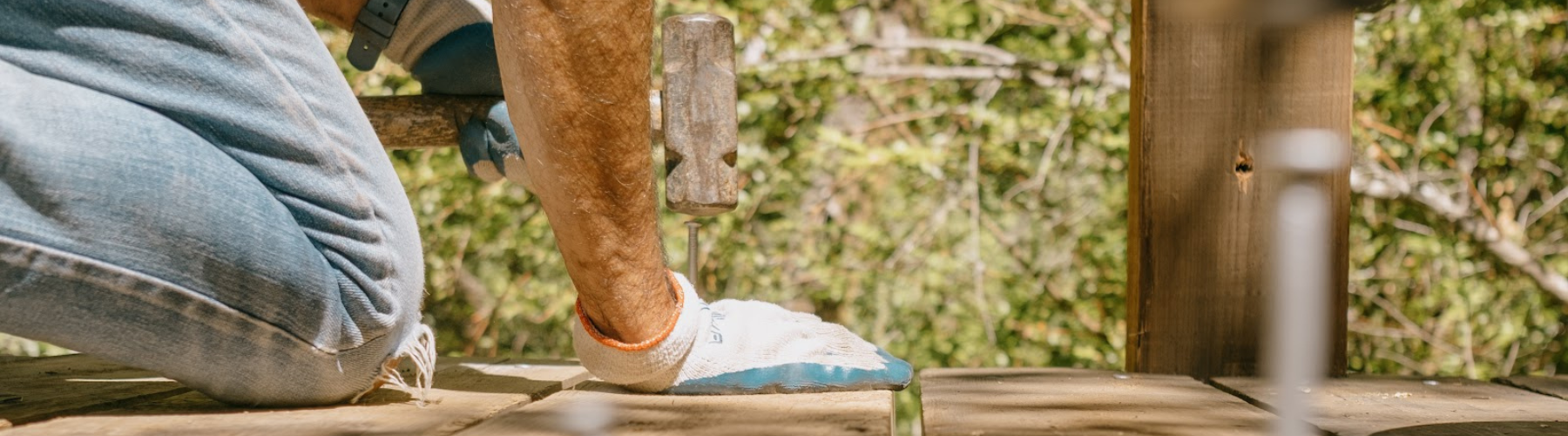 Image shows a person hammering a nail on a small bridge.