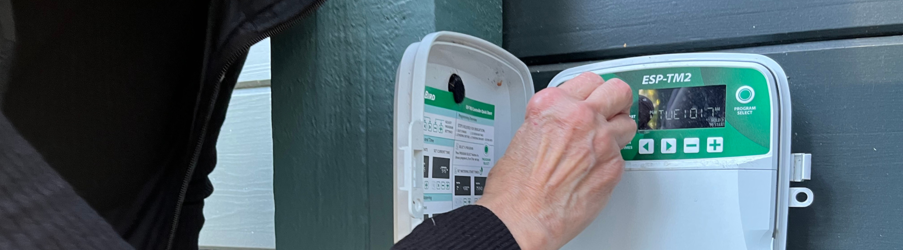 A person adjusts an irrigation controller.