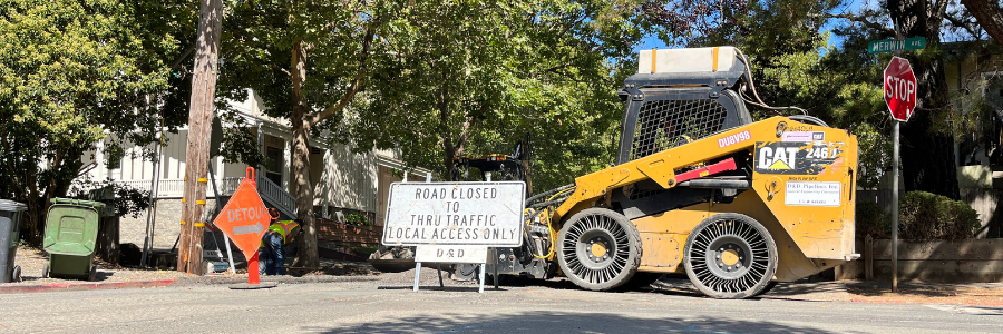 Heavy construction equipment and signage on a residential street.