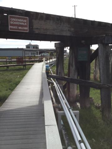 Boardwalk under wood trellis with sign reading Greenbrae Boardwalk Private Walkway