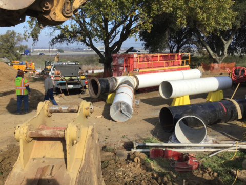 Construction site with workers, piping, and equipment