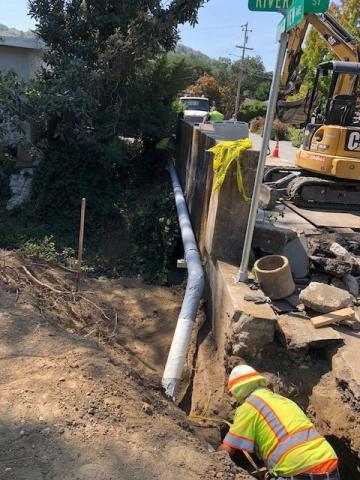 Construction worker in a hole with pipeline