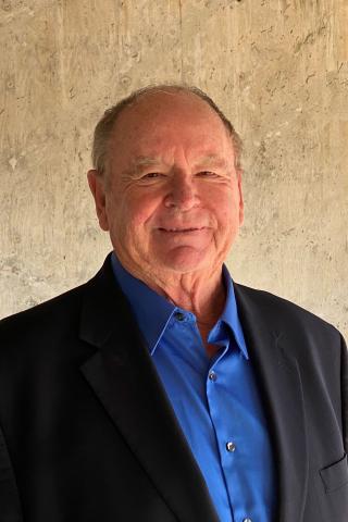 A man posed for a photo in front of a concrete backdrop