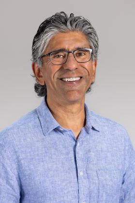 A man posed for a photo in front of a plain backdrop