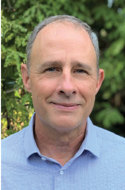 A man posed for a photo with leaves in the background