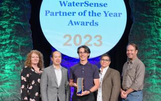 People stand in front a large, white graphic reading "WaterSense Partner of the Year Awards."