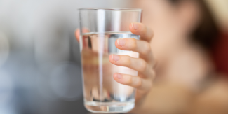 Close up image of person's handing holding a glass of water