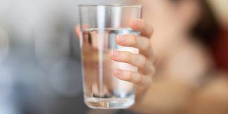 A hand holding a glass of drinking water