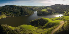 A reservoir set among rolling green hills.