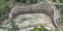 A large, brown retaining wall surrounded by trees.