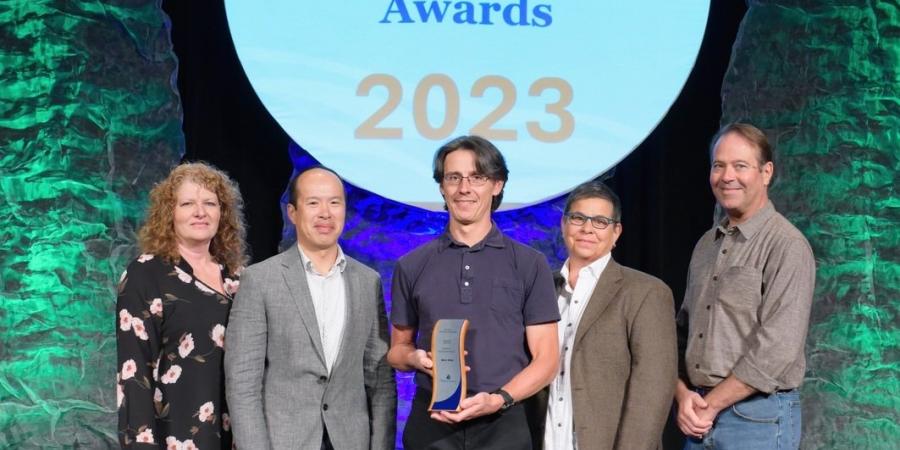 People stand in front a large, white graphic reading "WaterSense Partner of the Year Awards."