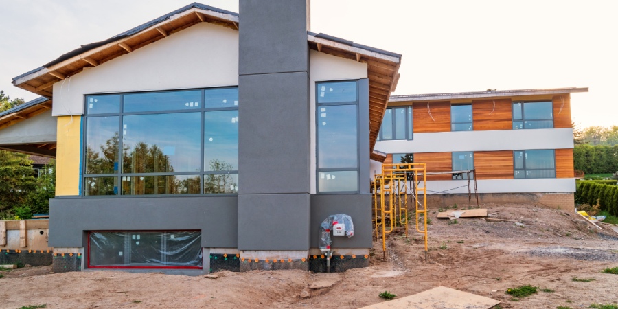 A newly built home is surrounded by dirt and undeveloped landscape. 