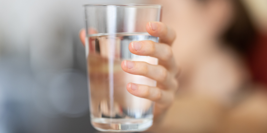 Close up image of person's handing holding a glass of water