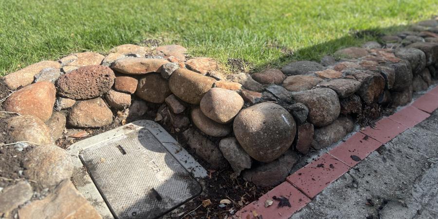 Water meter box surrounded by stones and grass