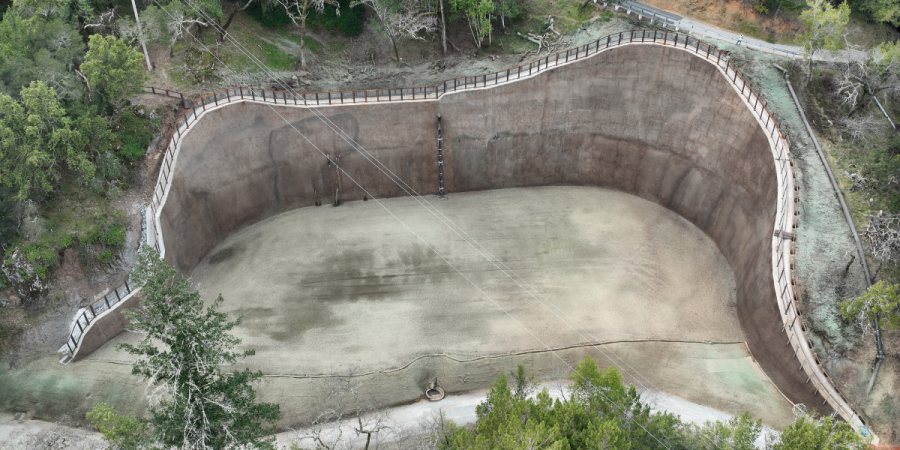 A large, brown retaining wall surrounded by trees.